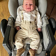 Kevan a rejoint le concours — aidez-le/la à gagner de superbes lots ! baby, child, clothing, cushion, footwear, furniture, happy, high_chair, indoor, infant, pants, person, portrait, relaxing, seat, shirt, shoes, smile, suspenders, wood_floor