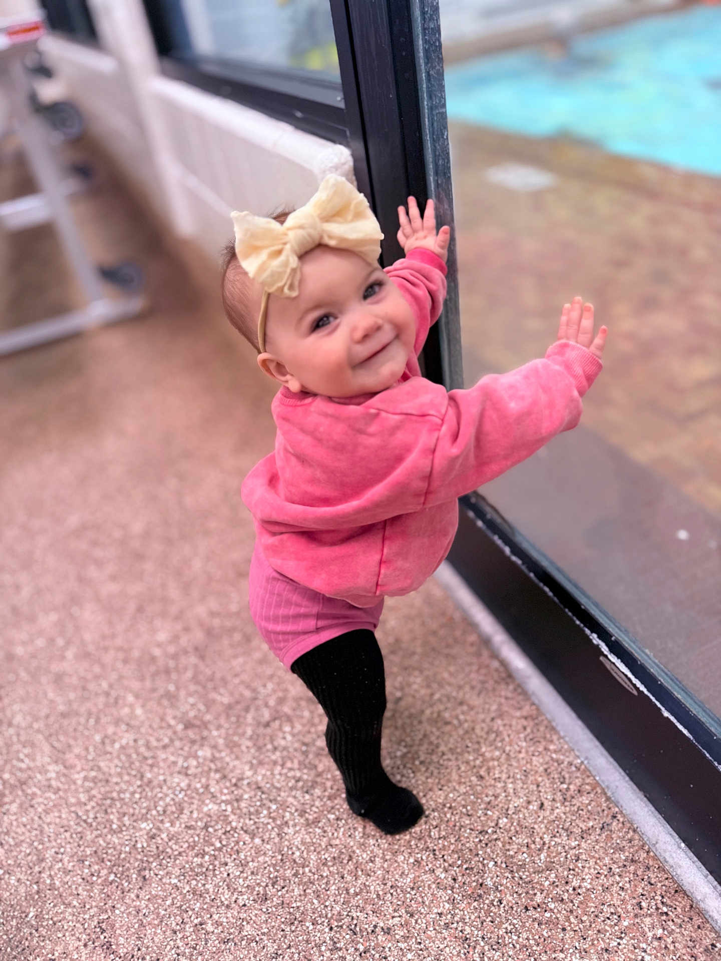 Wren joined the competition — help win amazing prizes! baby, child, girl, bow, pink_sweater, black_tights, standing, glass_door, pool, outdoor, smile, happy, headband, window, floor, reflection, person, cute, portrait, toddler