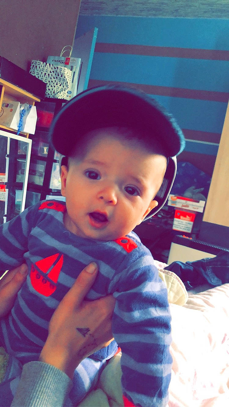 Tiago participe au concours pour gagner de l'argent avec cette photo : baby, baseball_cap, blue, bookcase, cap, child, cool, electric_blue, finger, fun, happy, hat, headgear, mouth, nose, person, shelf, sitting, thumb, toddler