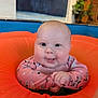 Ivy is registered to the contest to win money with this photo: baby, infant, swim_ring, pool, water, pink_suit, cute, smiling, chubby_cheeks, floating, playful, child, happy, indoors, water_droplets, bright_colors, face, hands, skin, eyes