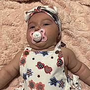 Amara is registered to the contest to win money with this photo: baby, pacifier, headband, blanket, infant, clothing, patterned_outfit, stars, stripes, face, cheeks, arm, soft_texture, cute, lying_down, baby_girl, closeup, indoor, comfort, child