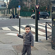 Kiran participe au concours pour gagner de l'argent avec cette photo : car, checkered_outfit, child, city, clothing, concrete, crosswalk, curly_hair, daytime, footwear, metal_pole, outdoor, pedestrian, pointing, sidewalk, street, toddler, traffic_light, traffic_sign, urban