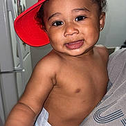 Jay'Marrionn joined the competition — help win amazing prizes! toddler, child, baby, red_cap, diaper, indoor, person, smile, hand, face, human, cute, expression, holding, refrigerator, kitchen, adult_hand, playful, casual, portrait