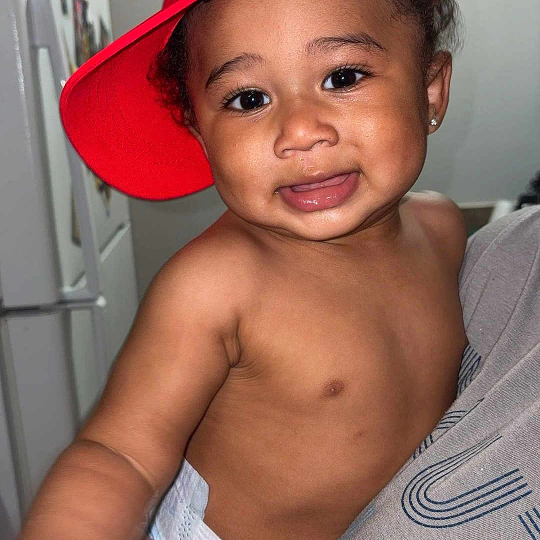 Jay'Marrionn joined the competition — help win amazing prizes! toddler, child, baby, red_cap, diaper, indoor, person, smile, hand, face, human, cute, expression, holding, refrigerator, kitchen, adult_hand, playful, casual, portrait
