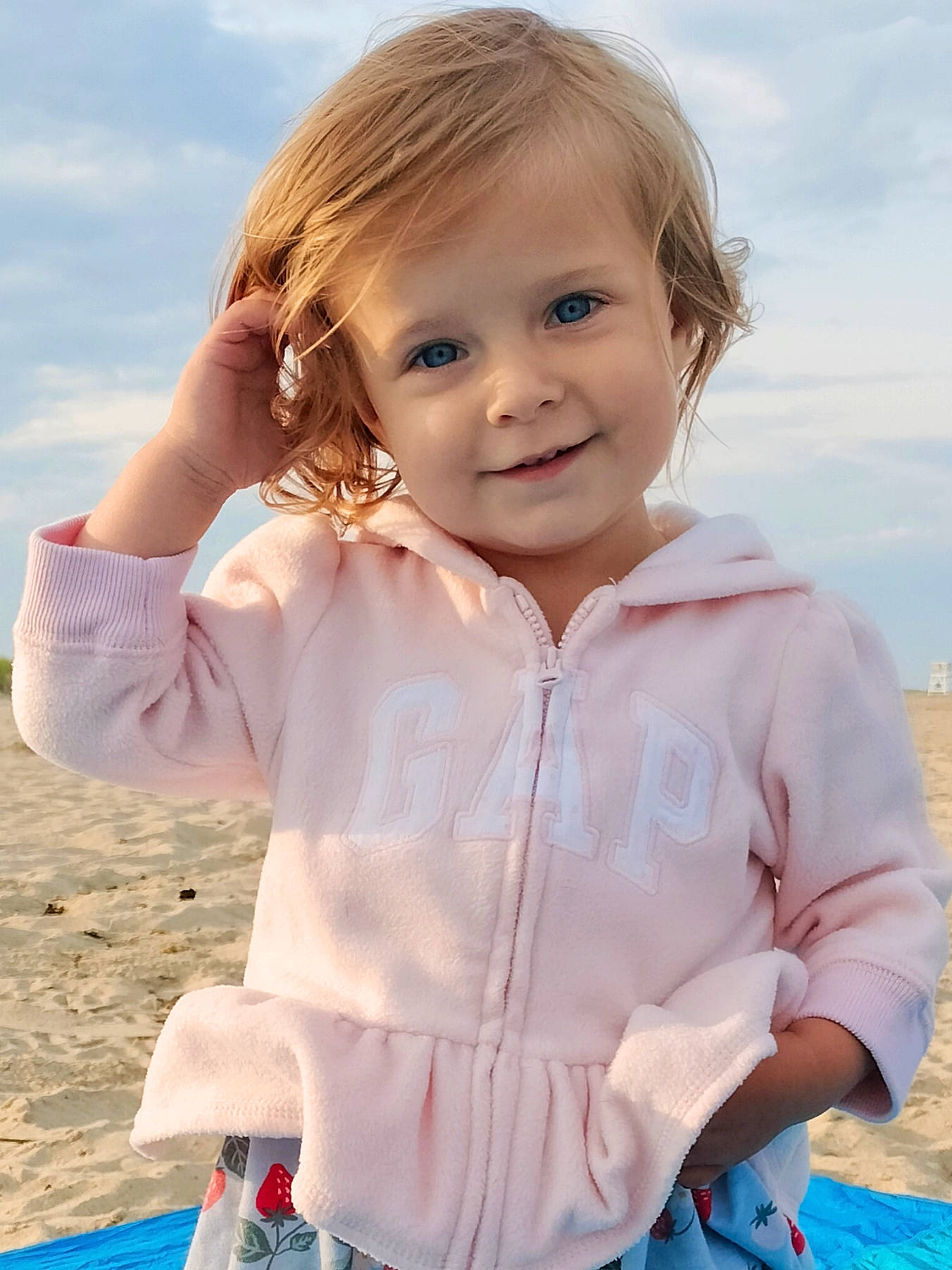 Briar is registered to the contest to win money with this photo: baby_toddler_clothing, beach, blond, blue, child, cloud, face, facial_expression, fun, gesture, grass, hairstyle, happy, joy, people_in_nature, person, skin, sky, sleeve, smile