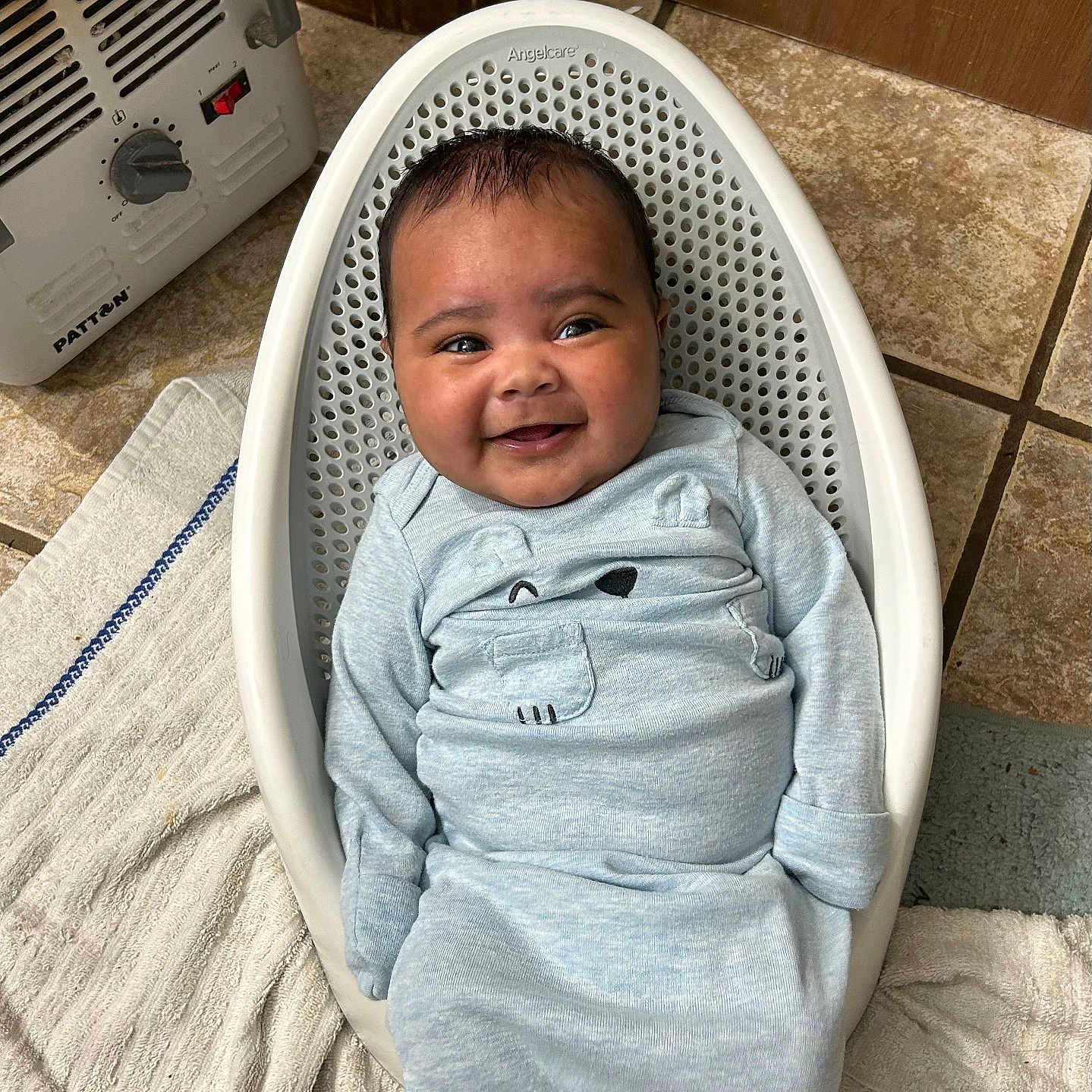 Kyeson joined the competition — help win amazing prizes! baby, infant, smiling, blue_outfit, basket, plastic_basket, tiled_floor, towel, heater, indoors, cute, happy, child, portrait, floor, clothing, person, head, face, cozy