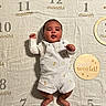 baby, infant, milestone_blanket, months, 2_months, romper, striped_clothing, cute, smiling, raised_fists, lying_down, indoor, fabric_background, decorative, wooden_circle, happy, child, portrait, newborn, celebration