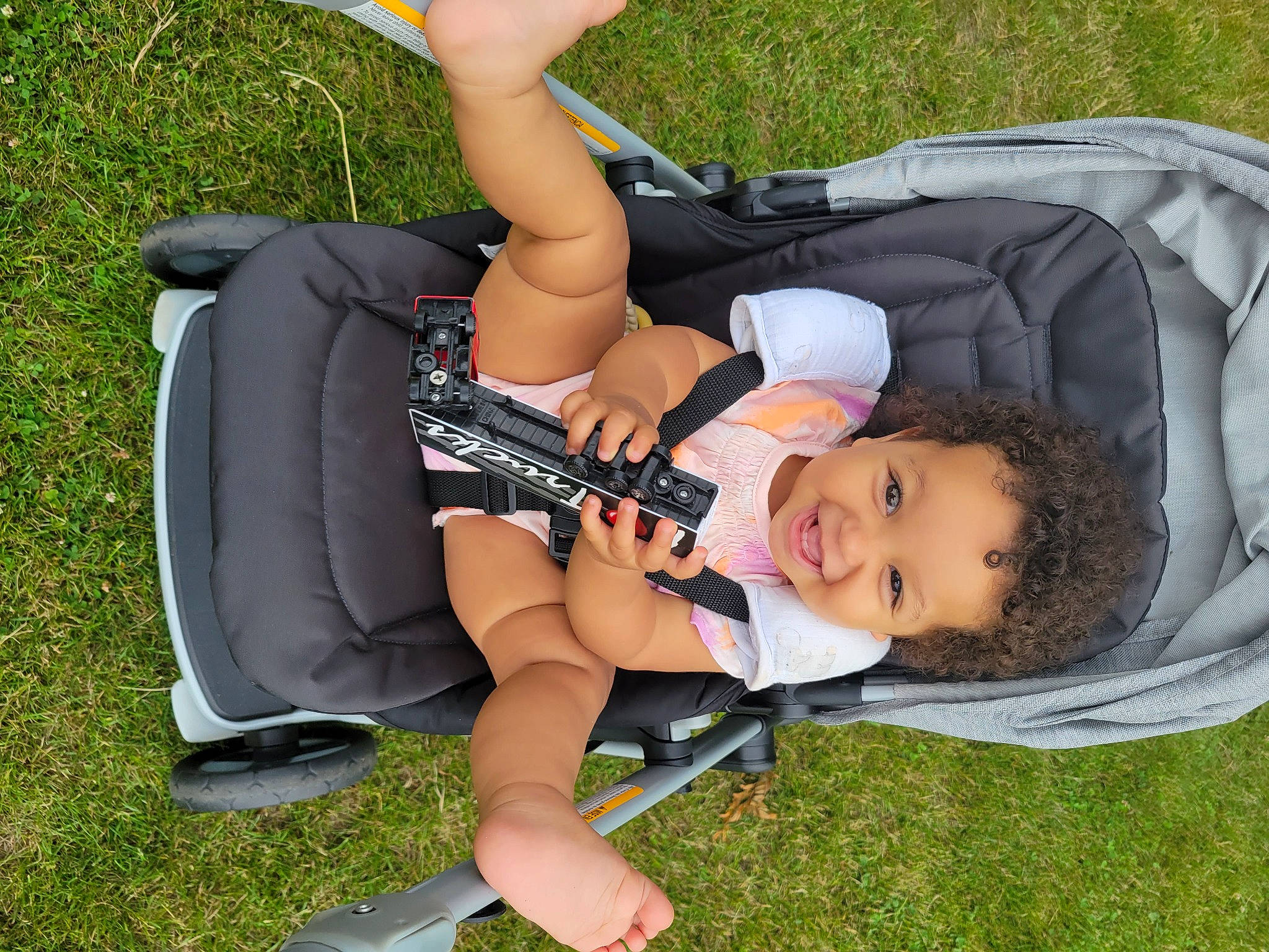 Tiana is registered to the contest to win money with this photo: arm, baby_products, comfort, fun, grass, human_leg, joint, joy, knee, lap, lawn, leg, leisure, person, plant, recreation, shoe, shorts, sneakers, sunglasses