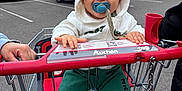 Malone a rejoint le concours — aidez-le/la à gagner de superbes lots ! baby, child, shopping_cart, pacifier, hoodie, green_pants, white_shoes, parking_lot, supermarket, cars, outdoor, smiling, person, clothing, retail, toddler, happy, urban, daytime, cute