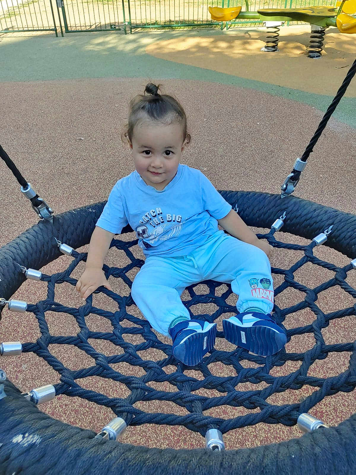 Ayden participe au concours pour gagner de l'argent avec cette photo : toddler, child, playground, swing, rope_swing, blue_clothing, marvel, sneakers, outdoor, daylight, smile, curly_hair, top_knot, play, fun, park, fence, rope, casual, happy