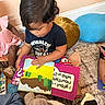Gael is registered to the contest to win money with this photo: child, toddler, book, reading, carpet, cushion, indoor, play, learning, group, kids, colorful, footwear, clothing, floor, engagement, education, early_learning, curiosity, home