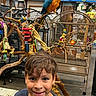 Carlos is registered to the contest to win money with this photo: animal, bird, birdcage, boy, child, colorful, face, feathers, hair, happy, indoor, parrot, perch, person, pet_store, playground, rope, smile, toys, wood