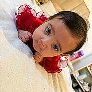 Hasna a rejoint le concours — aidez-le/la à gagner de superbes lots ! baby, infant, red_dress, blanket, bedroom, bed, face, eyes, hands, cute, child, indoors, person, clothing, soft, home, baby_girl, portrait, lying_down, curious