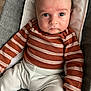 Lazarus is registered to the contest to win money with this photo: baby, infant, child, face, eyes, clothing, striped_sweater, pants, hand, seat, cushion, fabric, indoor, portrait, person, skin, head, expression, closeup, young