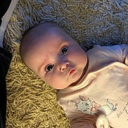 Lottie joined the competition — help win amazing prizes! baby, infant, child, pink_clothing, cartoon_cat, rug, texture, face, eyes, cute, soft_lighting, indoor, portrait, hand, apparel, person, newborn, expression, lying_down, closeup