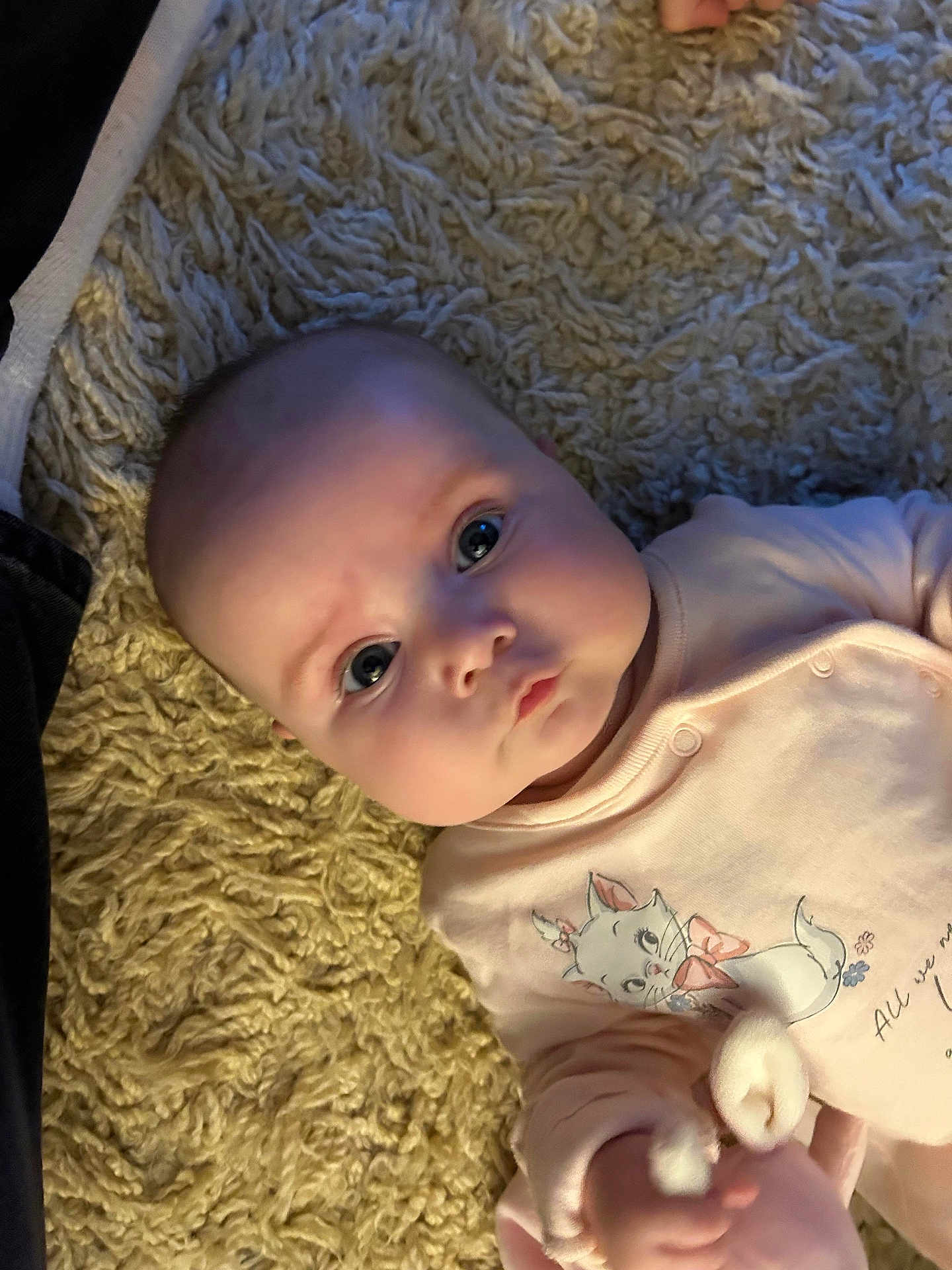 Lottie joined the competition — help win amazing prizes! baby, infant, child, pink_clothing, cartoon_cat, rug, texture, face, eyes, cute, soft_lighting, indoor, portrait, hand, apparel, person, newborn, expression, lying_down, closeup