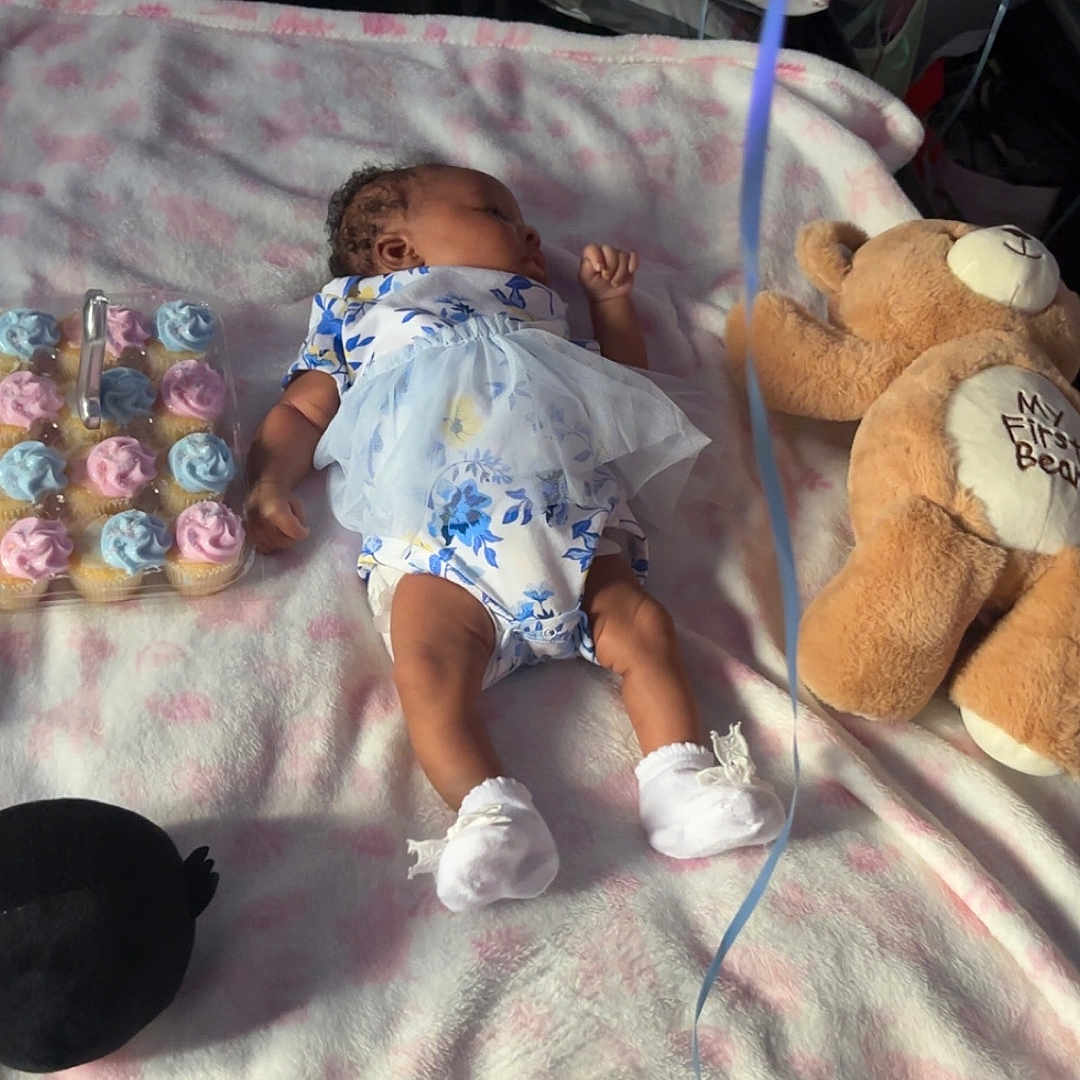 Quaasia is registered to the contest to win money with this photo: baby, blanket, cupcakes, teddy_bear, ribbons, bed, pillow, sleeping, soft_toys, footwear, clothing, floral_pattern, celebration, indoors, comfort, child, pastel_colors, toys, rest, nap