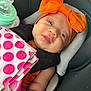 baby, infant, newborn, car_seat, headband, orange_bow, blanket, polka_dot, bottle, face, eyes, cheeks, skin, cute, portrait, closeup, seat, fabric, sleepy, adorable
