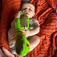 Liam is registered to the contest to win money with this photo: baby, child, infant, slipper, green, orange, blanket, texture, diaper, hand, foot, face, curious, playful, soft_light, indoor, cute, person, lying, holding