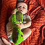 baby, child, infant, slipper, green, orange, blanket, texture, diaper, hand, foot, face, curious, playful, soft_light, indoor, cute, person, lying, holding