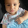 baby, blue_dress, car_seat, child, close_up, clothing, dress, eyes, face, fashion, floral_pattern, hand, indoor, infant, pastel_colors, photography, portrait, serious_expression, sitting, skirt