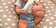 Aurora joined the competition — help win amazing prizes! baby, child, headband, bow, sneaker, footwear, denim_overalls, cushion, pattern, carpet, indoor, cute, infant, person, holding, sitting, closeup, soft_lighting, curious, foot