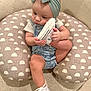 baby, child, headband, bow, sneaker, footwear, denim_overalls, cushion, pattern, carpet, indoor, cute, infant, person, holding, sitting, closeup, soft_lighting, curious, foot