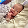 baby, smiling, blanket, bed, pillow, infant, cute, face, hand, soft, cozy, child, lying_down, indoors, happy, young, portrait, skin, expression, comfort