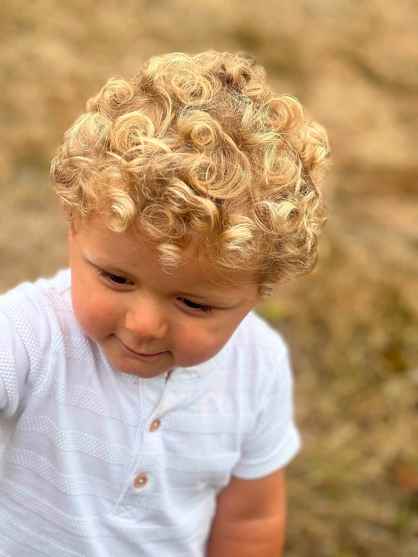 Liam a rejoint le concours — aidez-le/la à gagner de superbes lots ! child, toddler, curly_hair, blond_hair, white_shirt, portrait, outdoor, nature, smile, face, cute, young, innocent, closeup, person, childhood, soft_light, background_blur, happy, casual_clothing