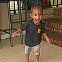 Achilles joined the competition — help win amazing prizes! child, toddler, barefoot, black_tshirt, gray_shorts, orange_accents, tile_floor, indoor, metal_chair, brick_steps, excited, motion_blur, happy, smiling, person, young, home_interior, playful, standing, casual_clothing