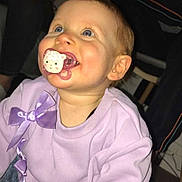 Zoé a rejoint le concours — aidez-le/la à gagner de superbes lots ! baby, child, pacifier, lavender_sweater, bow, smile, blue_eyes, rosy_cheeks, toddler, indoor, flash_photography, candid, cute, portrait, sitting, clothing, young_child, happy, family_moment, closeup