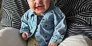 Nyla joined the competition — help win amazing prizes! baby, child, smiling, denim_jacket, headband, bow, cushion, pillow, patterned_leggings, socks, indoor, seated, happy, portrait, cute, infant, clothing, face, person, cozy