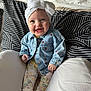 baby, child, smiling, denim_jacket, headband, bow, cushion, pillow, patterned_leggings, socks, indoor, seated, happy, portrait, cute, infant, clothing, face, person, cozy
