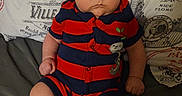 Jett is registered to the contest to win money with this photo: baby, child, infant, portrait, sitting, serious, face, eyes, hair, striped_outfit, red_clothing, navy_clothing, romper, couch, pillow, indoor, close_up, bare_legs, fabric, photography