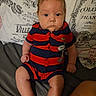 baby, child, infant, portrait, sitting, serious, face, eyes, hair, striped_outfit, red_clothing, navy_clothing, romper, couch, pillow, indoor, close_up, bare_legs, fabric, photography