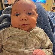Jett joined the competition — help win amazing prizes! baby, infant, child, portrait, close_up, face, eyes, wide_eyed, hand, fist, knitwear, beige_clothing, sweater, cozy, sitting, indoor, home, television, stuffed_animals, photography