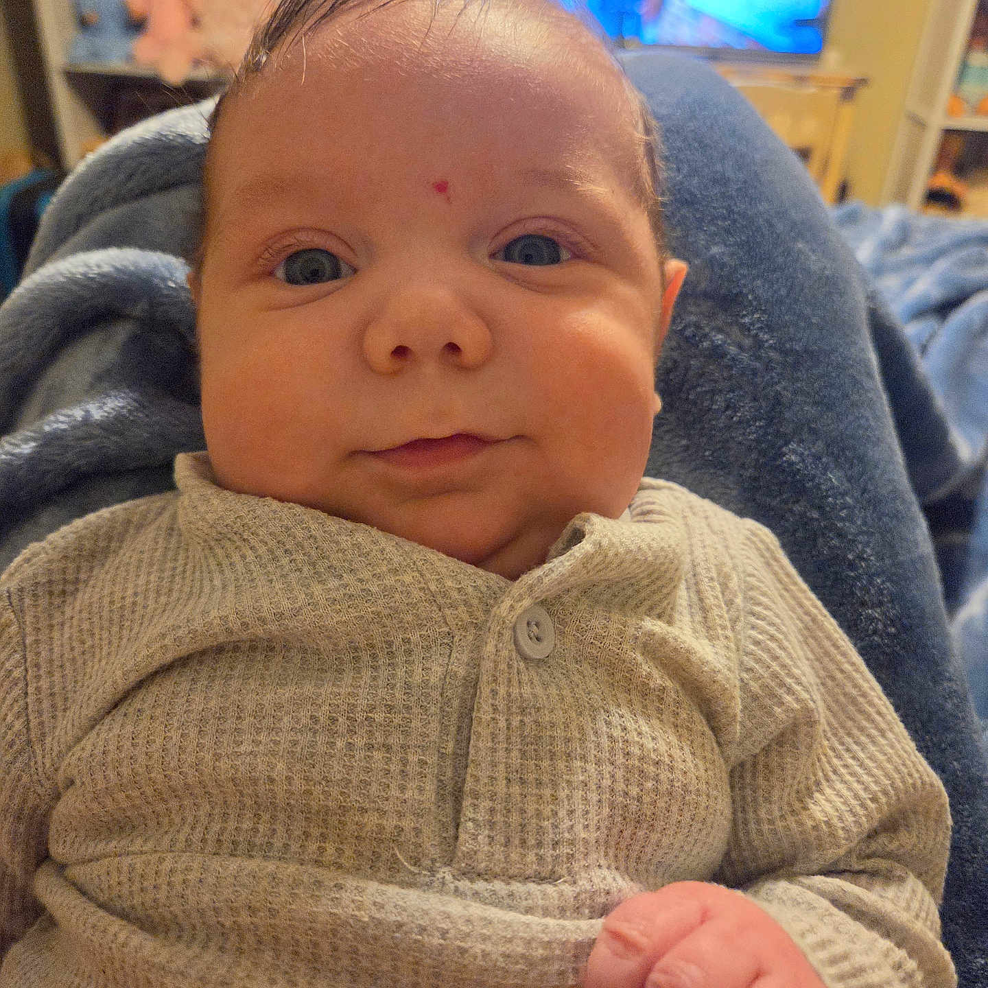 Jett joined the competition — help win amazing prizes! baby, infant, child, portrait, close_up, face, eyes, wide_eyed, hand, fist, knitwear, beige_clothing, sweater, cozy, sitting, indoor, home, television, stuffed_animals, photography