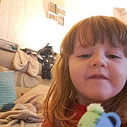 Jensen is registered to the contest to win money with this photo: child, young_child, selfie, face, hair, toy, stuffed_animal, bear_toy, couch, pillow, blanket, indoor, living_room, casual, comfort, home, smile, person, brown_hair, closeup