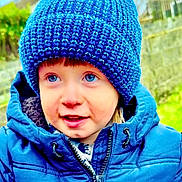 Kol joined the competition — help win amazing prizes! child, blue_hat, knit_hat, puffy_jacket, outdoor, winter_clothing, young_child, face, eyes, smile, curious, warm_clothing, nature_background, portrait, person, cute, happy, headwear, cold_weather, jacket