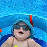 Aryn is registered to the contest to win money with this photo: baby, sunglasses, blue_hat, inflatable_pool, water, toy, summer, child, outdoor, smiling, sun_protection, floating, playful, bright_colors, close_up, summer_fun, skin, blue, yellow, happy