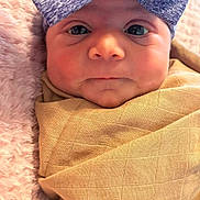 Amara joined the competition — help win amazing prizes! baby, infant, face, headband, bow, blanket, wrapped, close_up, pink, beige, soft, texture, newborn, portrait, cute, child, expression, indoors, person, cozy