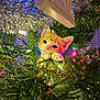 kitten, cat, christmas_tree, holiday_lights, tinsel, greenery, festive, cute, animal, pet, orange_cat, curious, indoors, decorations, christmas, playful, close_up, whiskers, paws, festivity