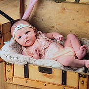 Amandine a rejoint le concours — aidez-le/la à gagner de superbes lots ! baby, baby_clothes, blanket, child, cozy, cute, decor, expression, floor, headband, indoors, infant, lace_outfit, newborn, portrait, resting, small_person, soft_lighting, wood, wooden_chest