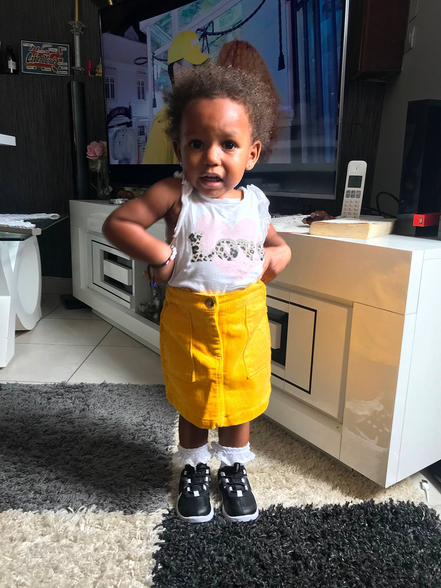 Emily a rejoint le concours — aidez-le/la à gagner de superbes lots ! child, footwear, leg, person, room, shoe, shorts, shoulder, standing, t_shirt, toddler, yellow