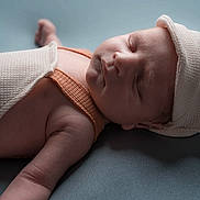 Leandro a rejoint le concours — aidez-le/la à gagner de superbes lots ! baby, sleeping, hat, blanket, infant, soft_texture, orange_clothing, peaceful, closeup, portrait, skin, resting, newborn, headwear, one_person, indoor, young_child, cute, baby_arm, blue_background