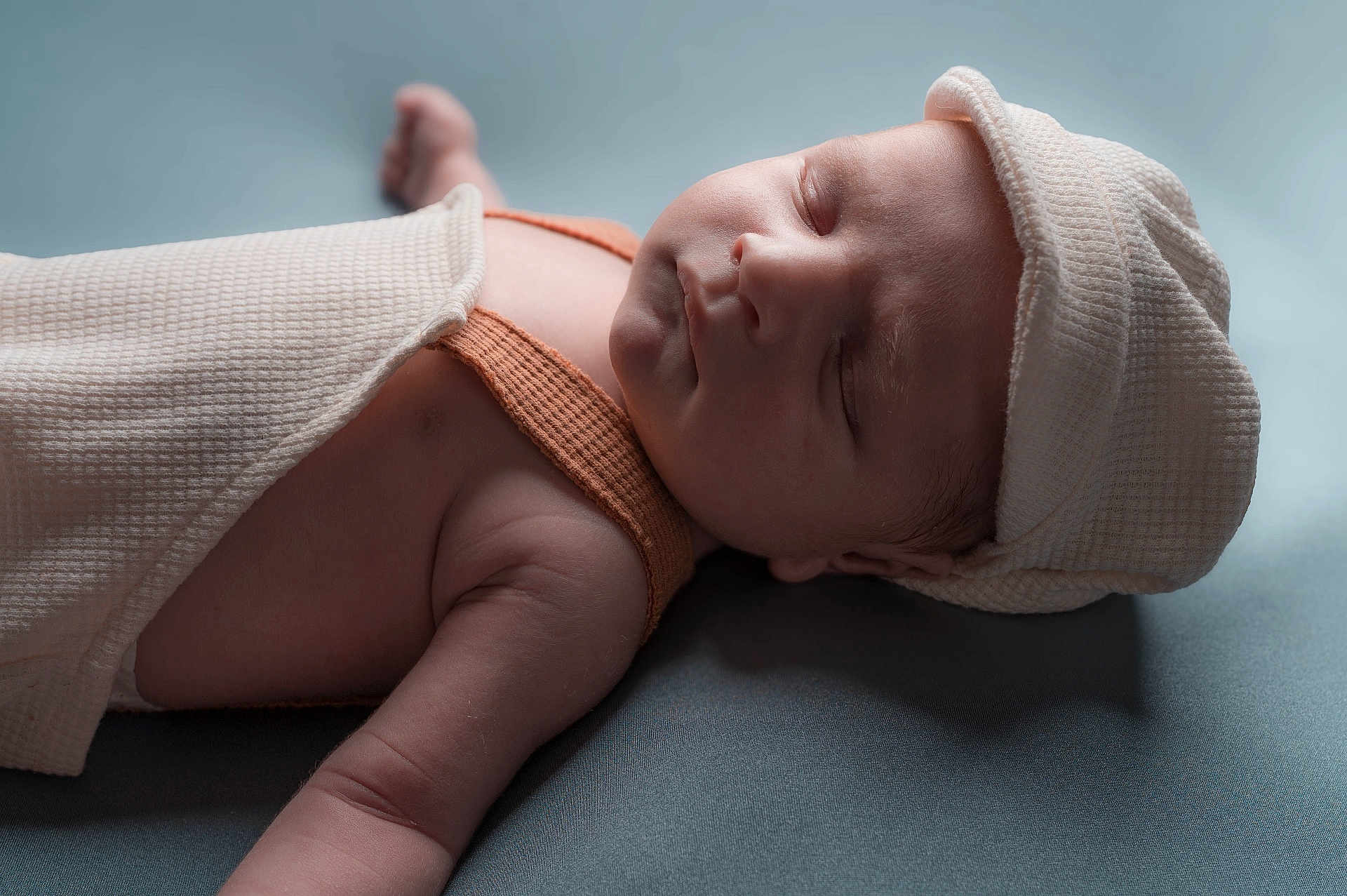Leandro a rejoint le concours — aidez-le/la à gagner de superbes lots ! baby, sleeping, hat, blanket, infant, soft_texture, orange_clothing, peaceful, closeup, portrait, skin, resting, newborn, headwear, one_person, indoor, young_child, cute, baby_arm, blue_background