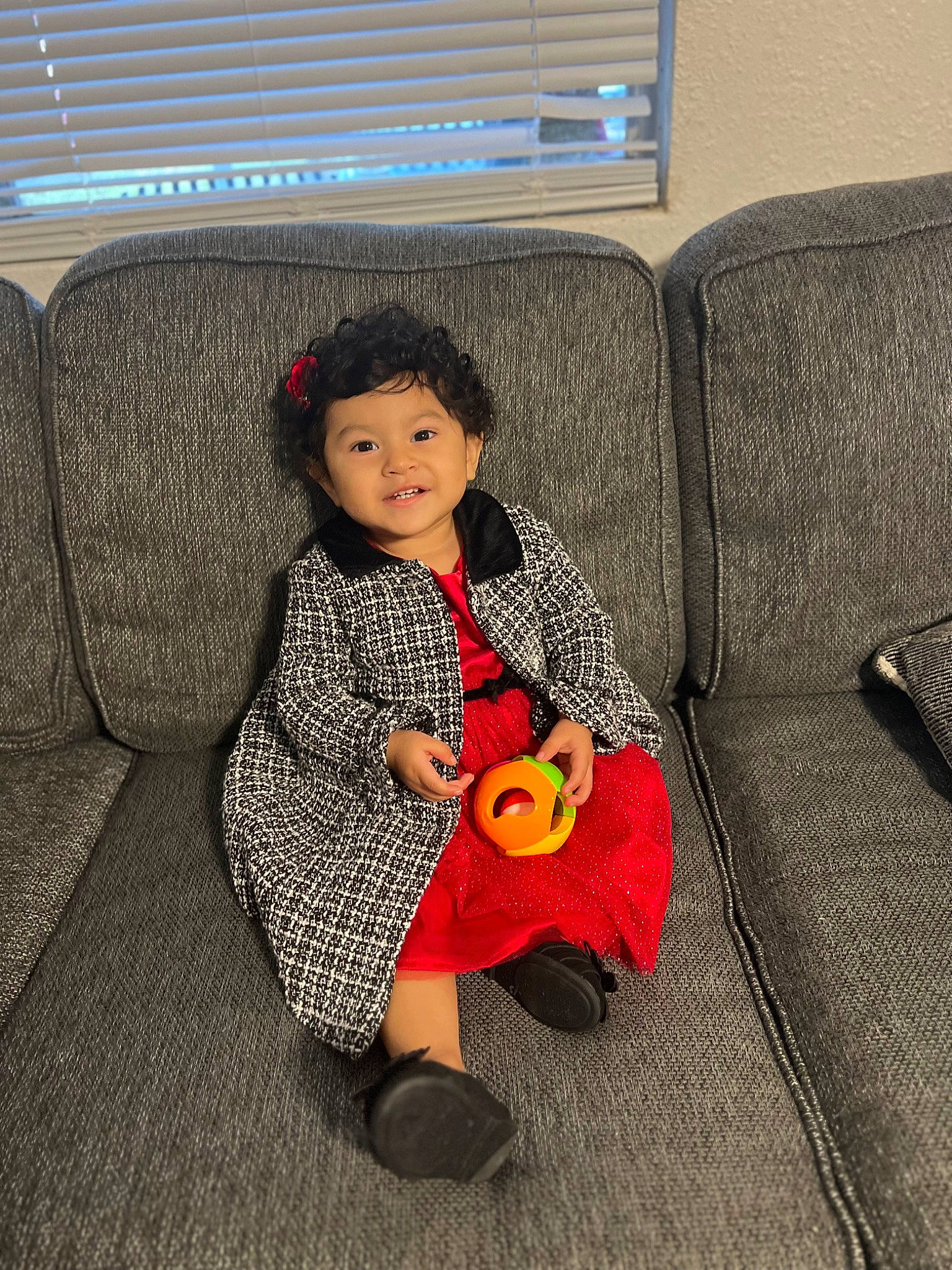 Alaia is registered to the contest to win money with this photo: baby_toddler_clothing, car_seat, chair, child, comfort, couch, face, flooring, furniture, head, human_leg, lap, living_room, pattern, person, room, sitting, stuffed_toy, suit, thigh