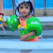 Kayo joined the competition — help win amazing prizes! child, toddler, pool, floaties, swimwear, hat, water_toy, curly_hair, outdoor, summer, playing, water, puddle_jumper, green, yellow, blue, palm_trees, background, cute, fun