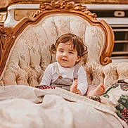 Brycen joined the competition — help win amazing prizes! toddler, child, sofa, vintage_furniture, quilt, blanket, curly_hair, indoors, portrait, relaxed, face, clothing, cute, seated, furniture, patterned, old_vehicle, background, warm_tones, casual