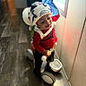 Dreko is registered to the contest to win money with this photo: black_pants, child, dinosaur, floor, fun, happy, helmet, home, indoor, play, red_shirt, ride, smile, sunlight, toddler, toy, tricycle, window, wooden_floor, young_child